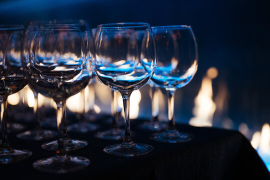 Row of Empty Wine Glasses with Blue Light and Fire Background
