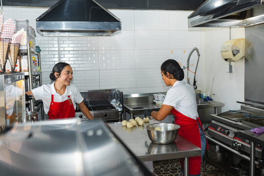 Two pastry chefs laughing and talking in a modern professional kitchen