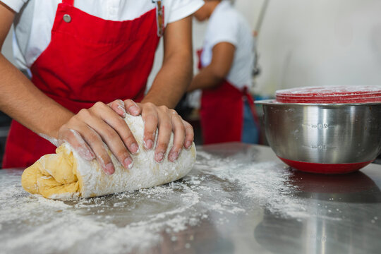 Chef hands kneading dough with flour in professional kitchen