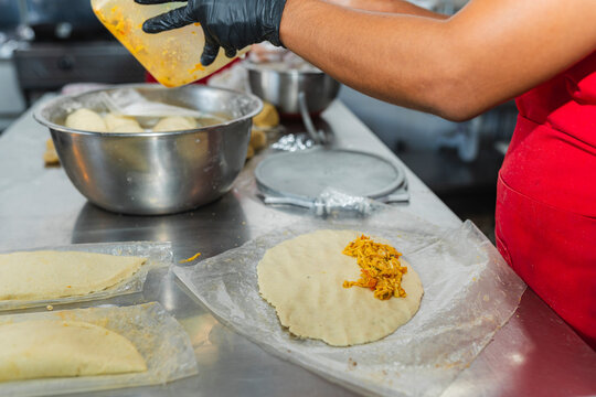Chef filling a chicken empanada on a professional steel table