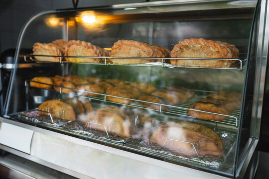Glass display case with baked empanadas and food on display