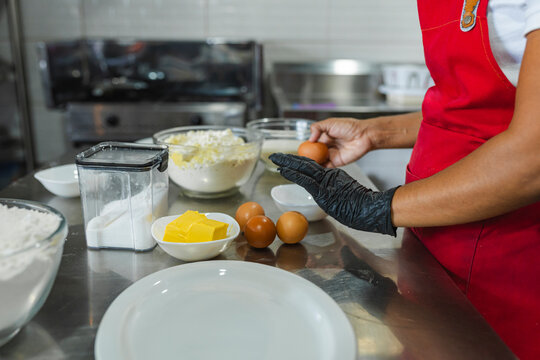 Cook wearing black gloves preparing eggs for a recipe