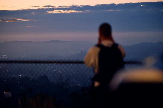 Man Observes Cityscape at Sunset from Elevated Position