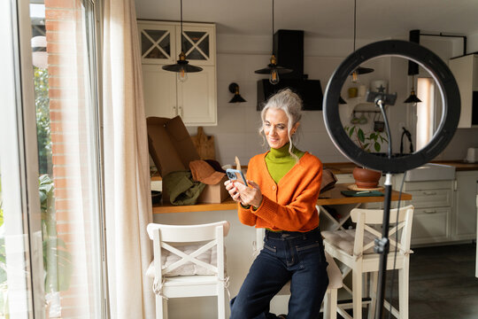 Senior woman recording content with phone at home