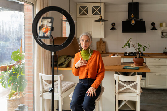 Senior woman recording content with phone at home