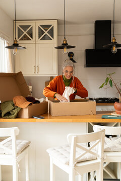Senior woman unboxing second hand clothes
