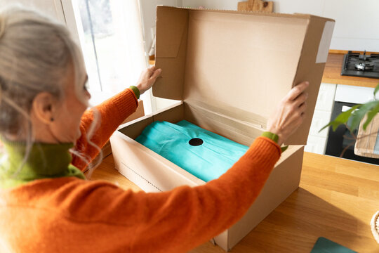 Senior woman opening parcel