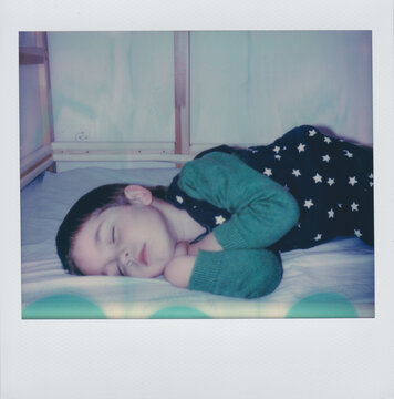 Polaroid portrait of a little boy sleeping peacefully in his bed