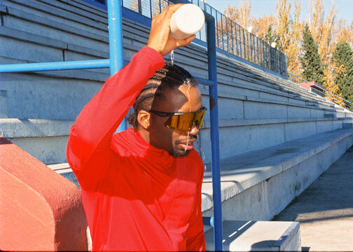 Professional runner pouring water over his head to cool off