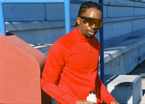 Film portrait of runner on sunlit outdoor track wearing sunglasses