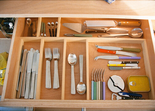 Wooden drawer with cutlery arranged in different compartments