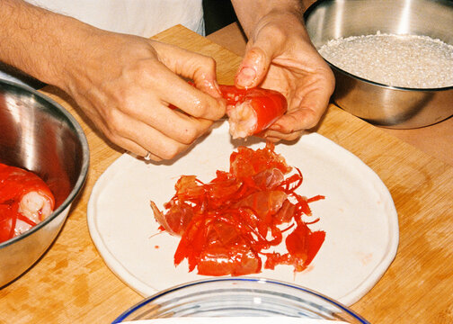 Anonymous person peeling shrimp at their kitchen