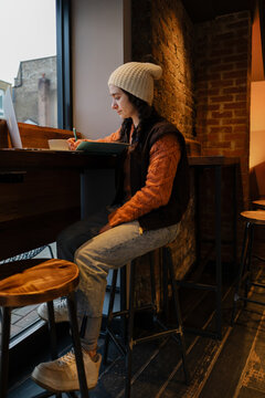 Student writing in notebook at coffee shop table