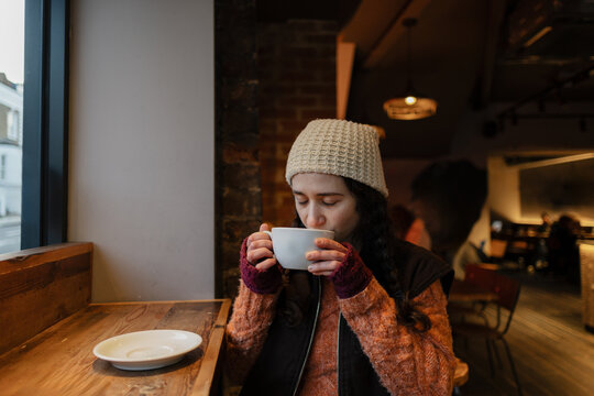 Woman enjoying hot coffee in cozy cafe during winter season