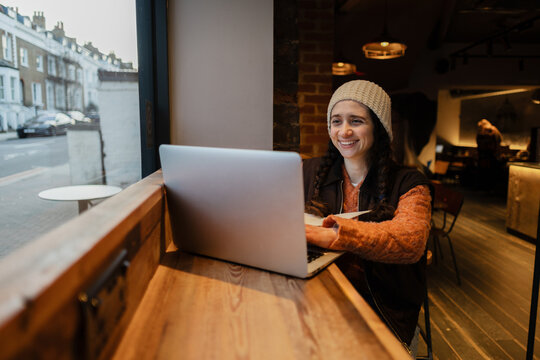 Smiling woman working on laptop in coffee shop