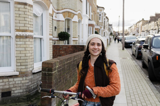 Woman smiling in London street pushing bicycle