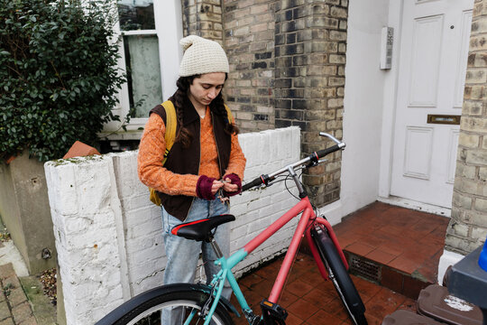 Cyclist securing bicycle with lock outside urban home