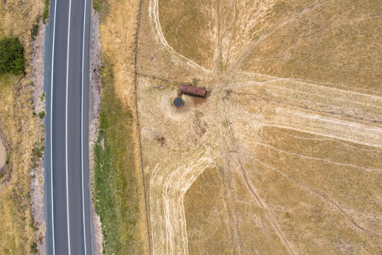 Animal tracks leading to a rusty water tanks alongside a country road