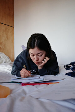 Person studying diligently lying on bed preparing for exams