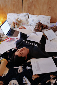 Student sleeping while studying for exams on bed