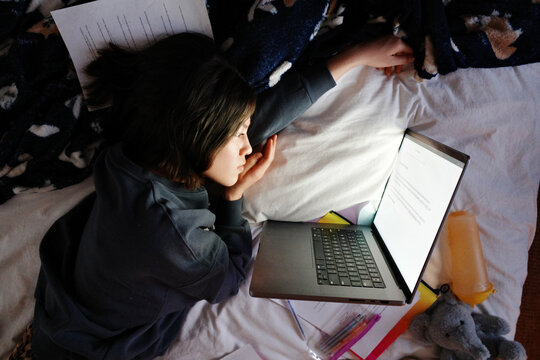 Student studying in bed feeling overwhelmed and tired