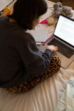 Person studying on laptop in bed