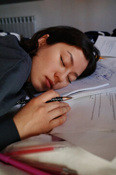 Person sleeping while studying, exhausted from exam preparation