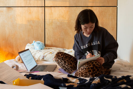 Person studying diligently preparing for exams in bed