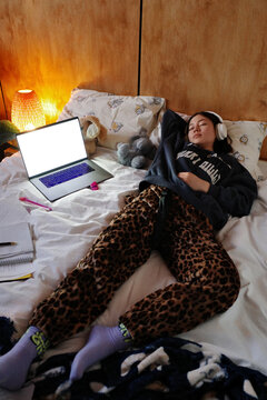 Student resting in bed while studying with laptop