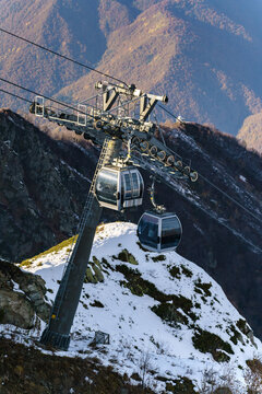 Cable car gondola climbing steep snowy rocky mountainside