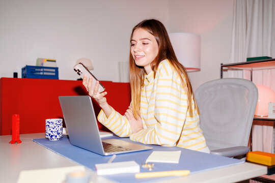 Woman using laptop and smartphone in home office