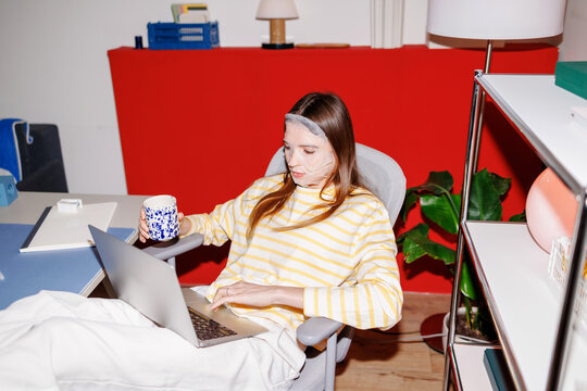 Woman with laptop and coffee at home office