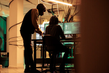 Online criminals analyzing script codes to hack government system, attacking sensitive sever and causing security breach. People hacking network and stealing information at night. © DC Studio