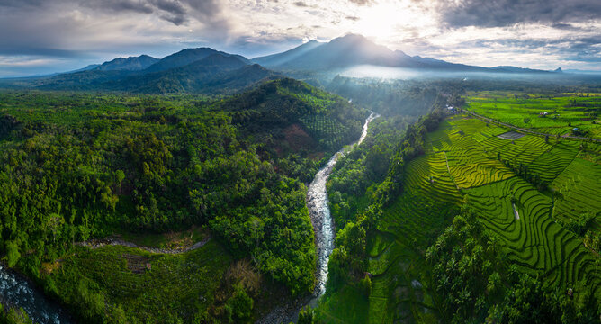 Beautiful morning view in Indonesia, panoramic landscape of rice fields with mountain ranges and clear sky