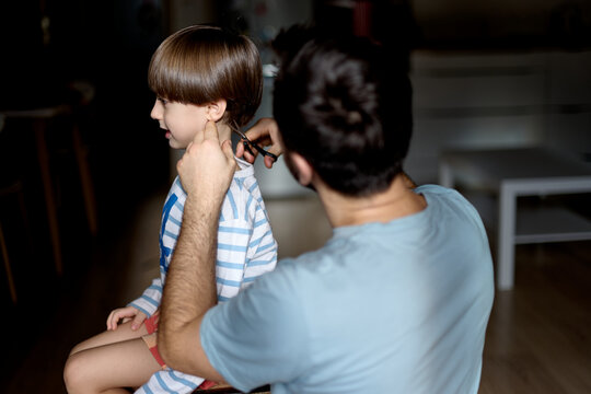 Father using hair clipper on smiling son