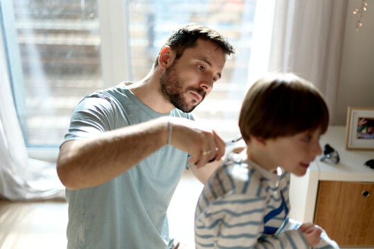 Father giving son a haircut at home
