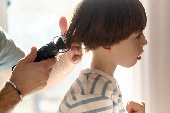 Father giving son a home haircut with clippers
