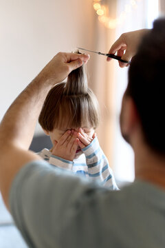 Father trimming son&rsquo;s bangs at home