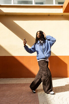 Young woman dancing and filming herself on smartphone