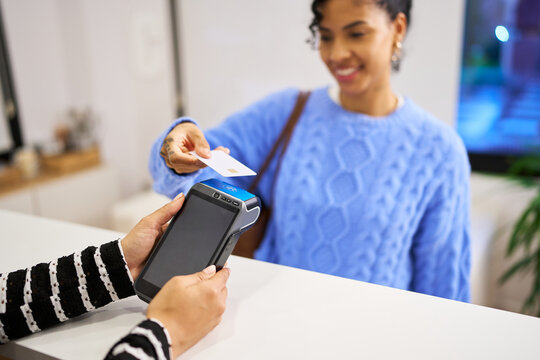 Customer making contactless payment at beauty salon reception