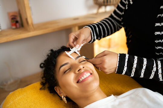 Woman getting microblading eyebrow measurement at beauty salon