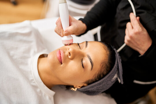 Woman receiving radio frequency facial treatment in salon