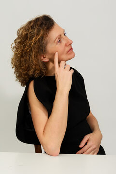 Woman Sitting in a Chair Deep in Thought With Hand on Her Face