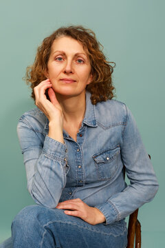 Smiling Woman Sitting in a Chair Against a Light Blue Background