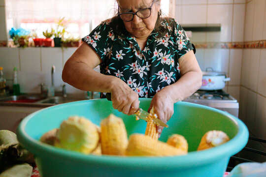 Senior Latina Woman Preparing Corn in Kitchen