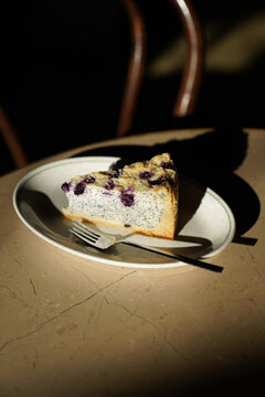 A piece of cheesecake with poppy seeds on a cafe table