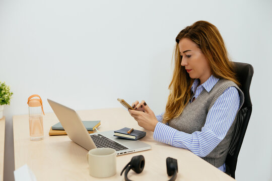 Woman working at office desk using smartphone