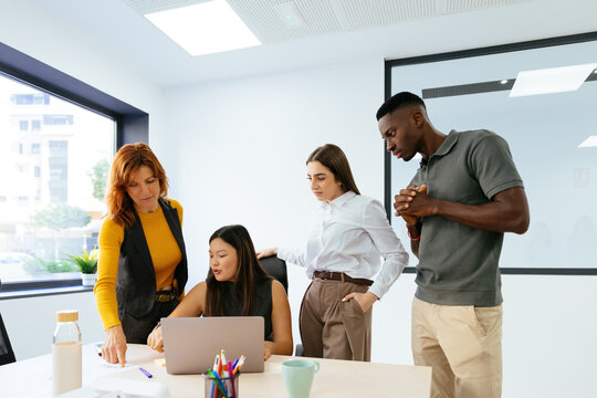 Diverse business people collaborating on laptop in office