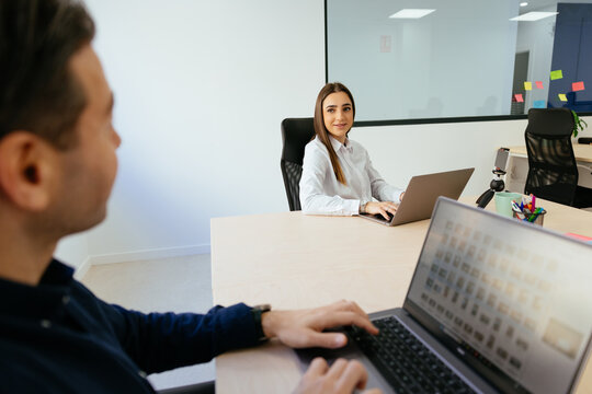 Coworkers collaborating in modern office using laptops