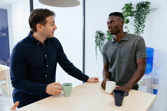 Diverse colleagues having coffee break communicating in office